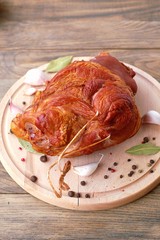 Smoked pork meat knuckle with garlic, pepper and laurel bay on wooden background