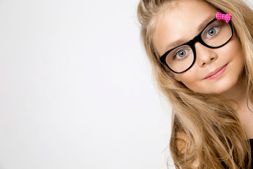 Portrait of a lovely little girl daughter in long blond hair and black glasses with pink bow which...
