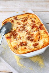 Gluten free meal roasted polenta with pork meat, spring onion, spices in white pan on grey cloth on white wooden background