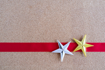 Fototapeta na wymiar Christmas golden and silver stars and red ribbon on cork board.