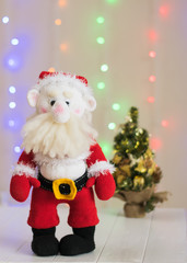 Knitted toy Santa Claus on a background of colorful bokeh.