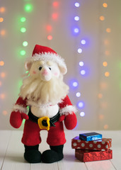 Knitted toy Santa Claus on a background of colorful bokeh.