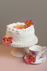 Homemade sweet pie with white cream decorated  natural flowers on pink table. vertical