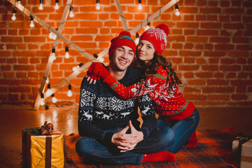 Happy loving young people having fun near the Christmas tree. Smiling couple celebrating New Year. Toned image.