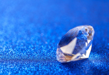 Grand royal pure diamond on blue sparkling sequins background, macro . Big brilliant closeup.