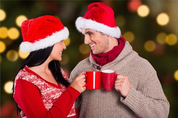 Happy couple in santa hat toasting coffee mugs