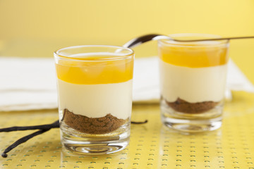 Dessert with mango topping, cream and cake in glasses