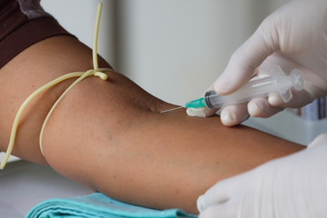 Doctor Injecting Patient With Syringe To Collect Blood