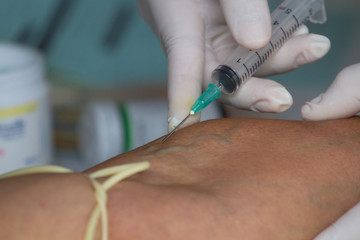 Doctor Injecting Patient With Syringe To Collect Blood