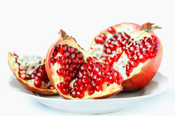 Ripe juicy pomegranate fruit (Punica granatum) in a white plate isolated on white background