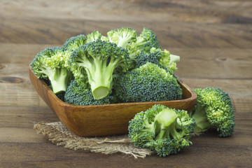 Raw broccoli in a bowl on wooden background