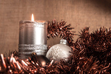 Christmas decorations: silver lit candle, baubles and tinsel