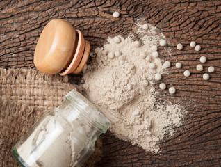White pepper grain and powder on wood background