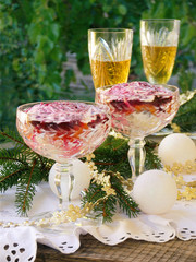 Traditional Russian New Year's salad herring and beet root. Layered vegetables and fish salad. Glasses with champagne. selective focus