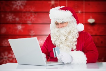 Santa claus doing online shopping with credit card on laptop