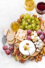camembert, grapes, wine and snacks on a white table, top view