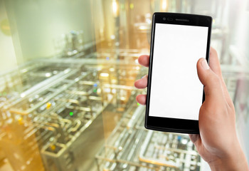 Hand holding smart phone on Manufacturing factory blurred background.