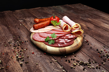 Food tray with delicious salami, pieces of sliced ham, sausage, tomatoes, salad and vegetable - Meat platter with selection