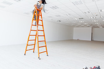 Worker electrician is using the wooden ladder to complete, check