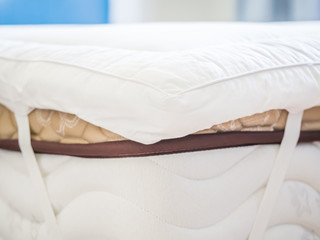 Closeup of white topper on the bed in the bedroom