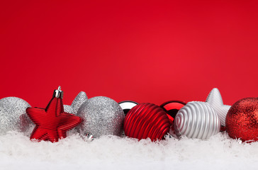 Christmas red background with baubles in snow