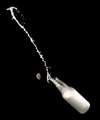 Fotobehang Milk bottle and splashes isolated on black background © showcake