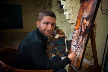 Closeup of painter artist working in a modern portrait oil canvas in his studio