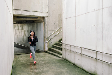 Urban female runner training on winter. Sporty woman running and exercising.