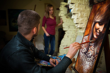 Obraz premium Young painter working on oil painting portrait in his art studio.
