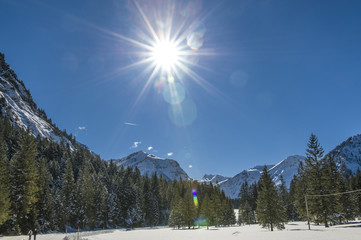 Blick auf verschneite Berglandschaft im Allgäu gegen die strahlende Sonne
