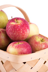 Closeup of apples in a wooden basket, on white background