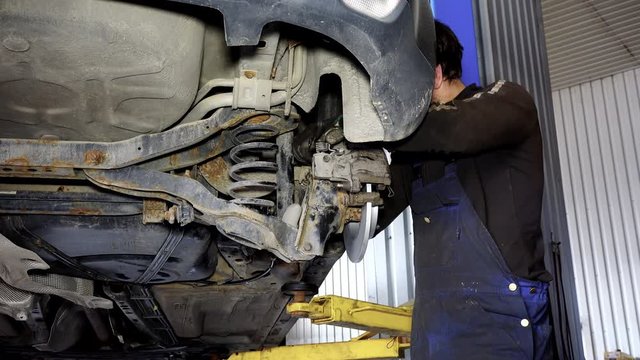auto mechanic guy working on car brake system.