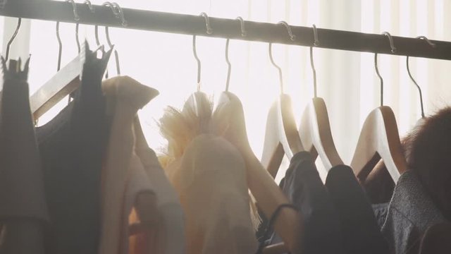 Close-up: a hanger for clothing. Designer clothing collection. Designer with a ready collection. Sunlight between hangers for clothes. Solar Design Studio. Atelier, bathed in natural sunlight.