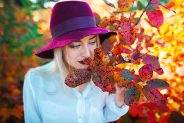 Autumn fashion portrait smiling woman wearing hat , red leaves background