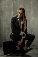 The girl in classic jacket, blouse and leather pants sits on a b