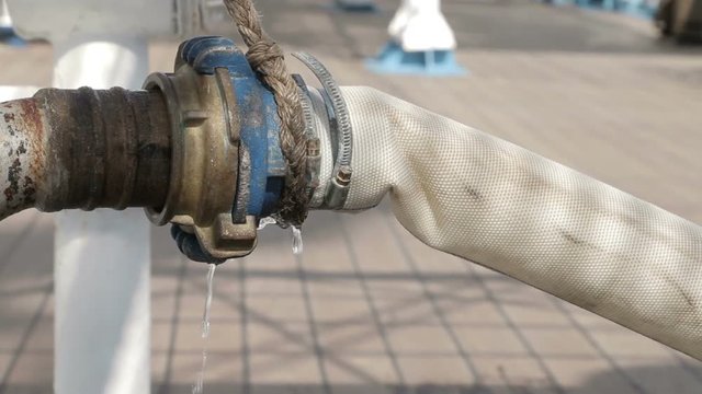 Close, fire hydrant spraying water, connected to hose line. Supply hose connects hydrant to fire pumper.