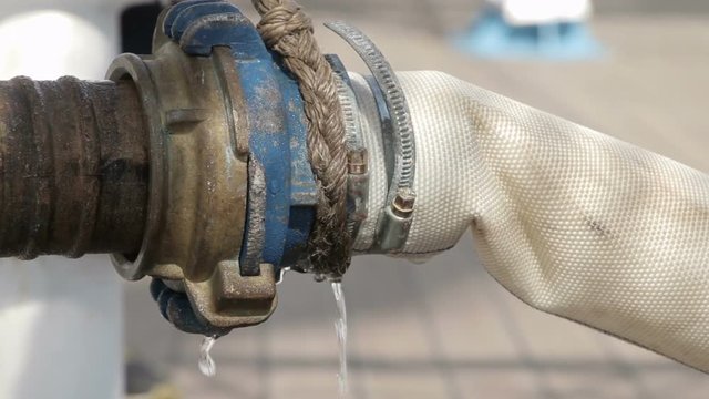 Close, fire hydrant spraying water, connected to hose line. Supply hose connects hydrant to fire pumper.