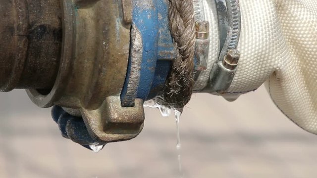 Close, fire hydrant spraying water, connected to hose line. Supply hose connects hydrant to fire pumper.