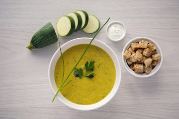 zucchini soup on a white wooden table with croutons