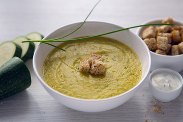 zucchini soup on a white wooden table with croutons