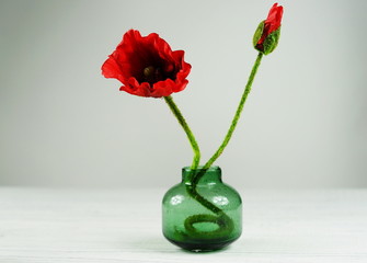 Home furnishings poppy flower in a green vase on a white background