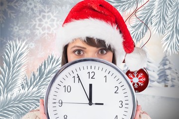 Woman in santa hat hiding behind a clock