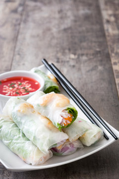 Vietnamese rolls with vegetables, rice noodles and prawns with sweet chili sauce  on wooden background
