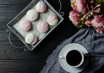 Pink and white marshmallows on a vintage tray, coffe and bouquet of flowers