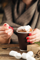 female hand holding cup of hot cocoa or chocolate with marshmall