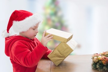 Excited boy in santa hat looking at christmas gifts