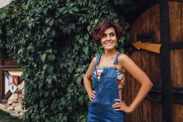 portrait of sexy young stylish smiling woman model in denim casual clothes outdoors among ivy