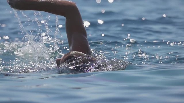 CLOSE UP, SLOW MOTION: Athlete competing in open water marathon swim competition