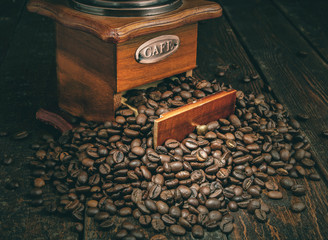 Coffee mill with coffee beans on dark background. Retro