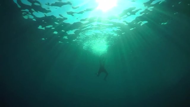 SLOW MOTION, UNDERWATER: Man drowning in deep ocean, struggling to reach surface